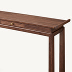 Detail of the console table's upturned right tabletop end, drawer front and slender legs.