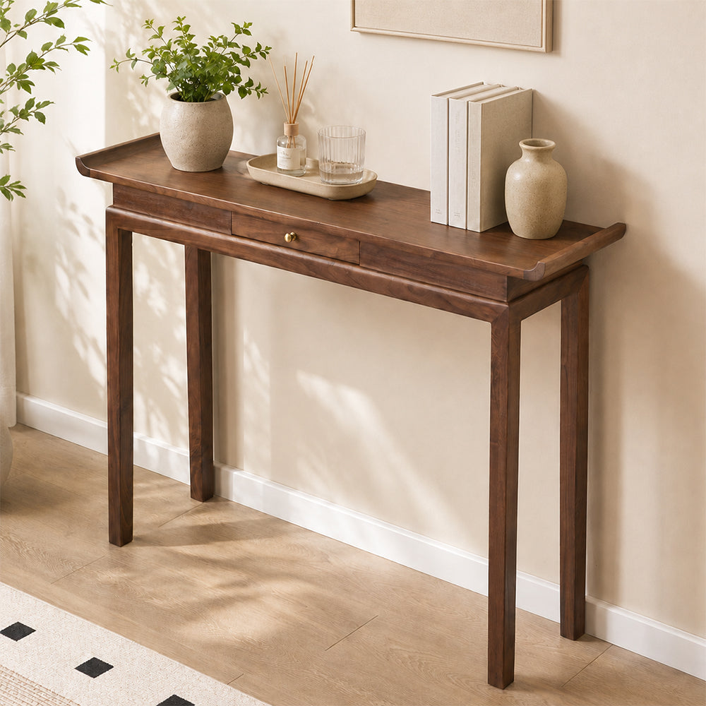 Angled view of the brown console table's narrow top, upturned ends and center drawer.