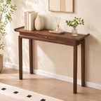 Brown drawer console table styled with vases and books against a pale entryway wall.