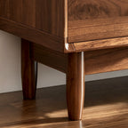 Close-up of the TV cabinet's rounded lower corner and tapered wood-tone leg.